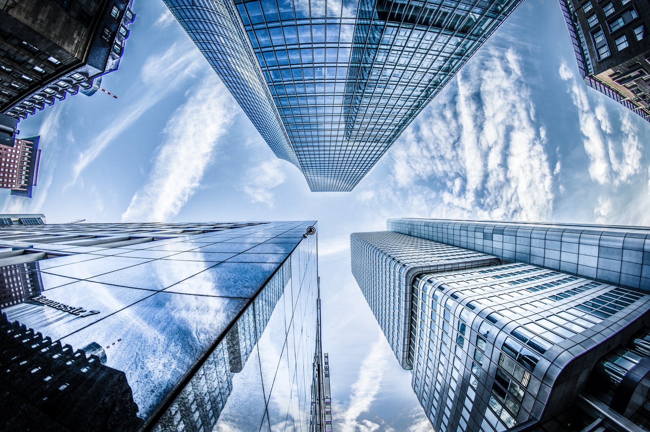 Low-angle Photo of Four High-rise Curtain Wall Buildings Under White Clouds and Blue Sky